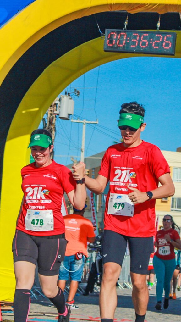 Casal cruzando a linha de chegada de mãos dadas